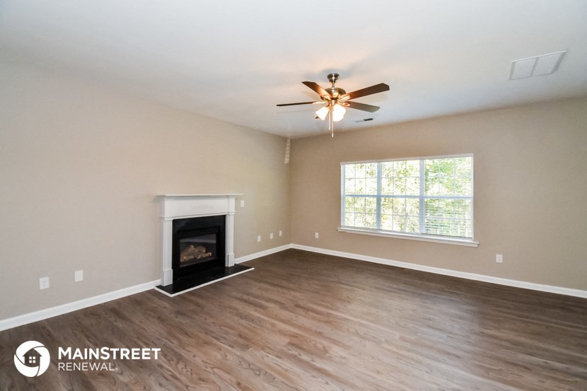 a living room with a fireplace and a ceiling fan