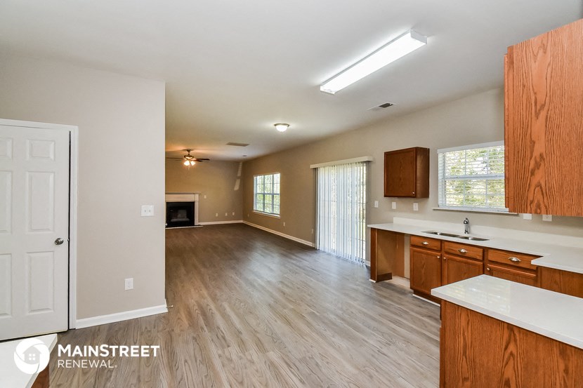 an empty living room and kitchen with wood flooring