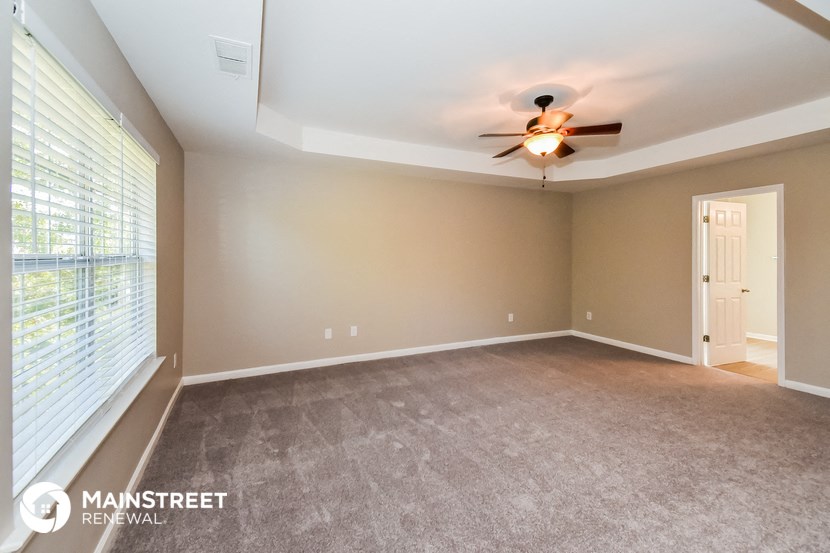 an empty living room with a ceiling fan and a large window