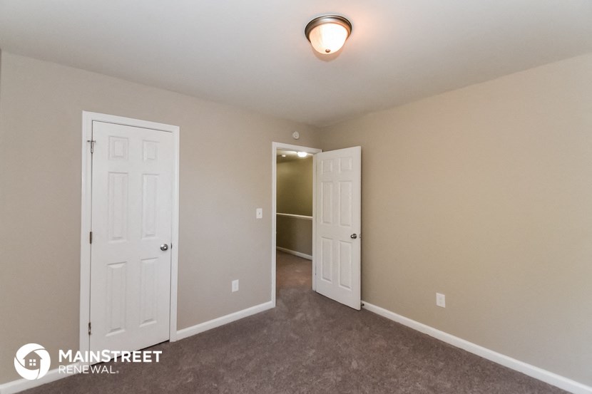 a bedroom with two doors and a closet and a door to a hallway