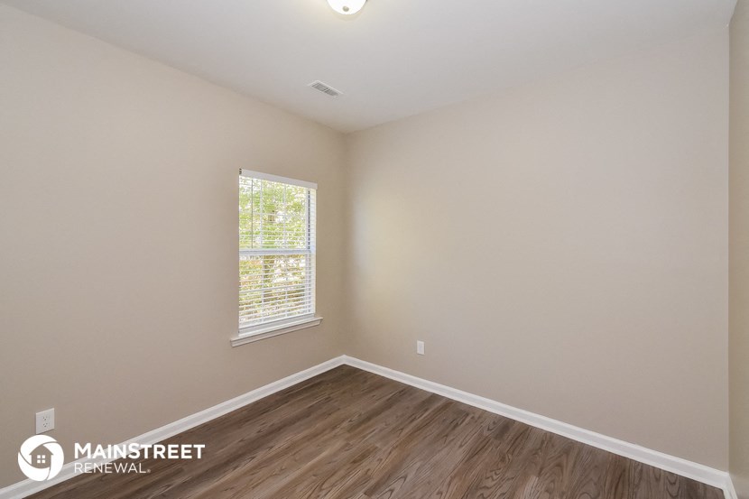 an empty room with wood flooring and a window