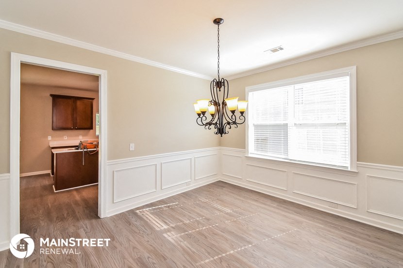 an empty dining room with a large window and a chandelier