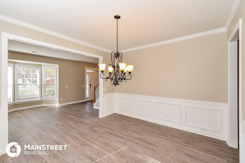 a dining room with white wainscoting and a chandelier