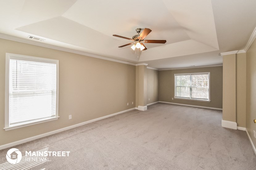 the living room of an empty home with a ceiling fan