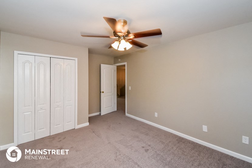 the master bedroom has a carpeted floor and a ceiling fan