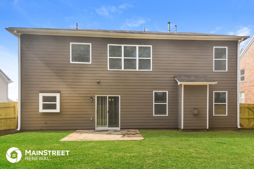 front view of a tan house with white windows and a green lawn