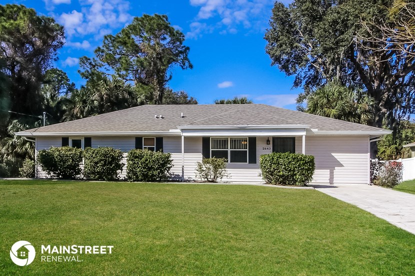a white house with a lawn and trees