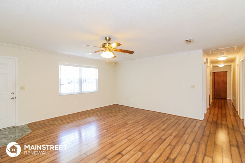 a empty living room with wood floors and a ceiling fan