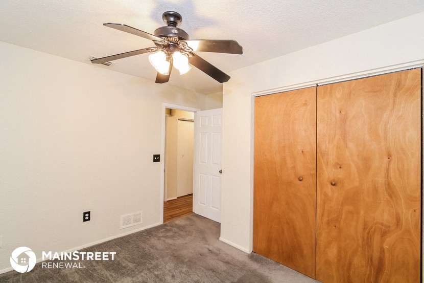a bedroom with a ceiling fan and a closet