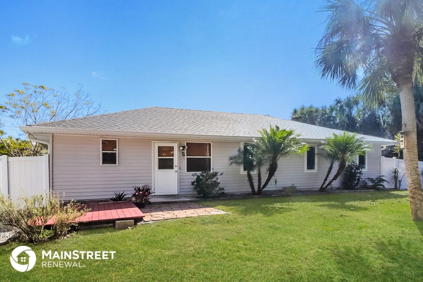 a small white house with palm trees and a lawn