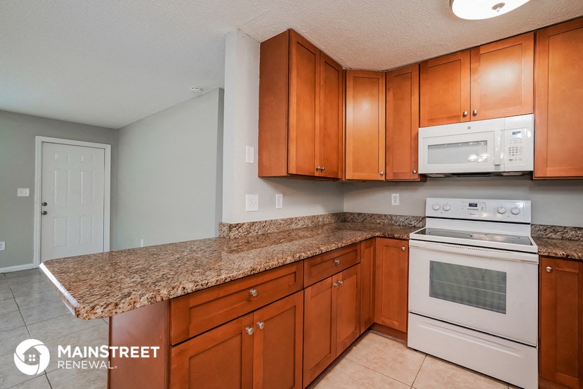 a kitchen with wooden cabinets and white appliances and granite counter tops