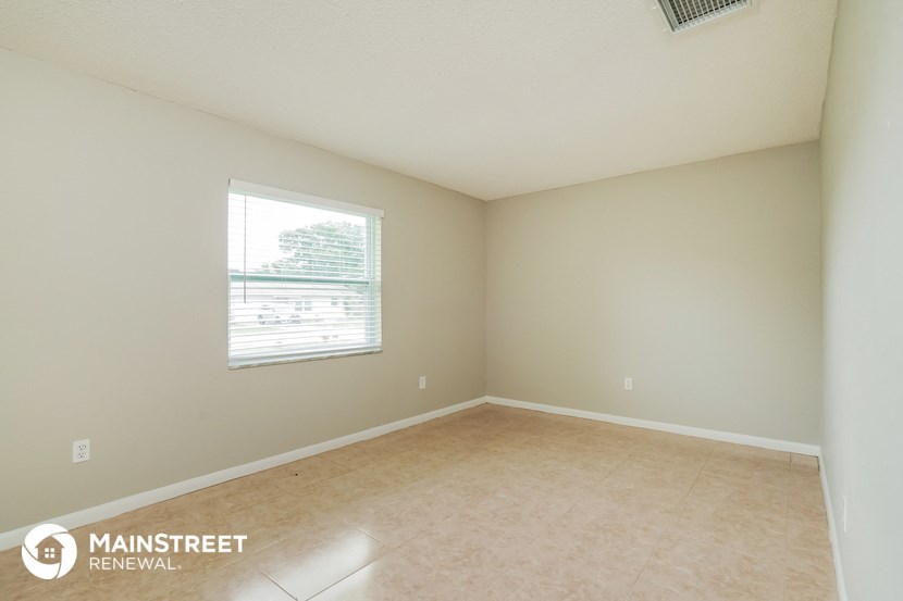 the spacious living room with a large window and beige tile flooring