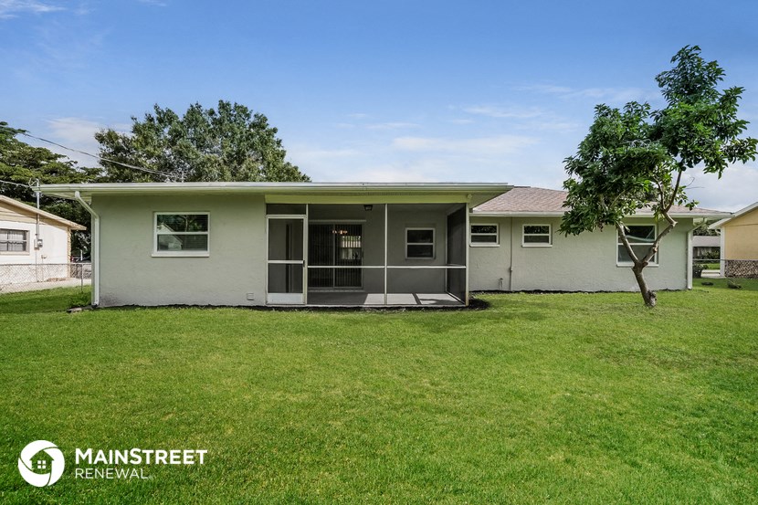 a small white house with a lawn and a tree