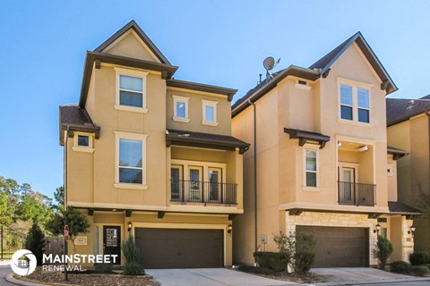 a tan house with two garages and a street sign