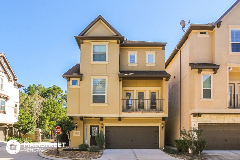 a yellow house with a driveway and a garage door