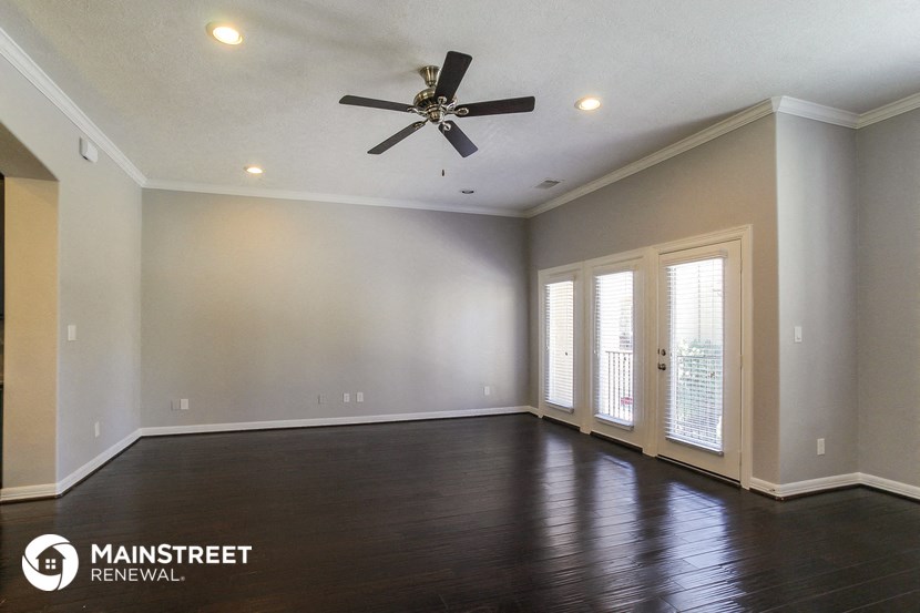 an empty living room with wood floors and a ceiling fan