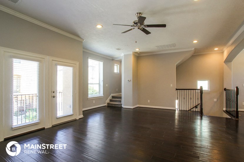 an empty living room with wood floors and a ceiling fan