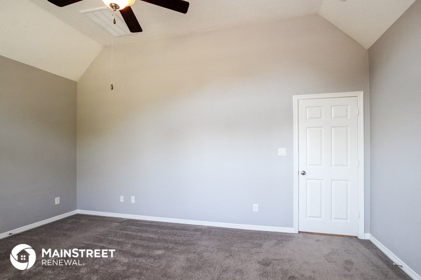 a empty living room with a ceiling fan and a white door