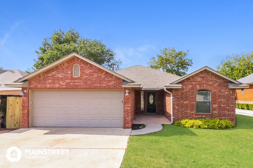 a brick house with a garage door and a lawn