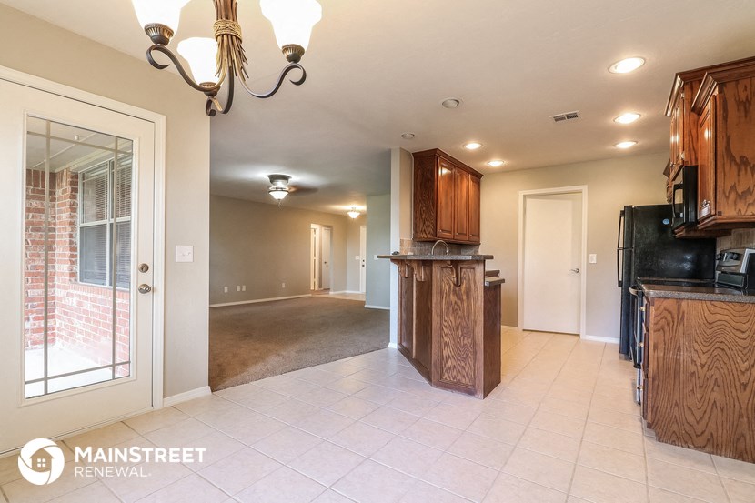 a kitchen and living room with wood cabinets and a door to theoyer