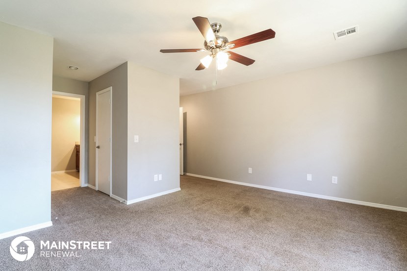 the spacious living room has carpet and a ceiling fan