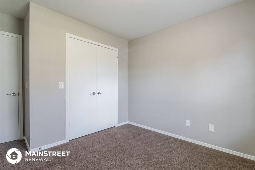 a bedroom with white walls and a door to a closet