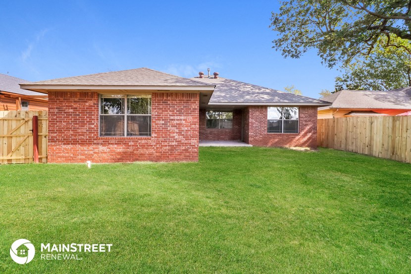 a backyard with a brick house and a wooden fence