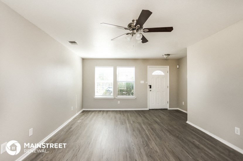 an empty living room with a ceiling fan and a door