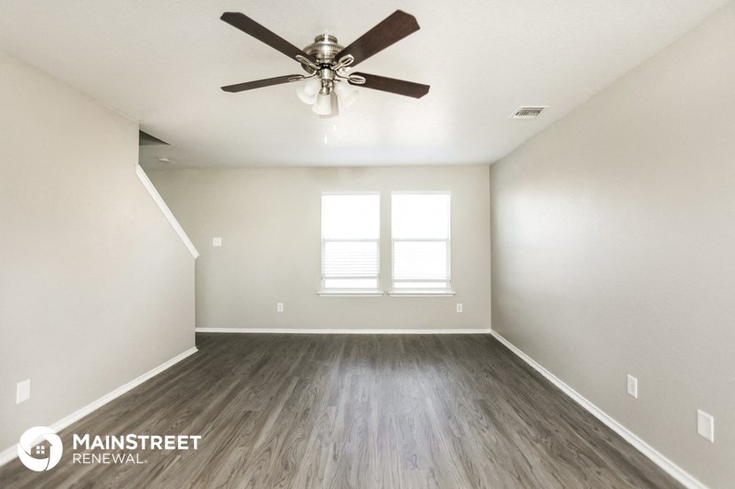 an empty living room with a ceiling fan and a window