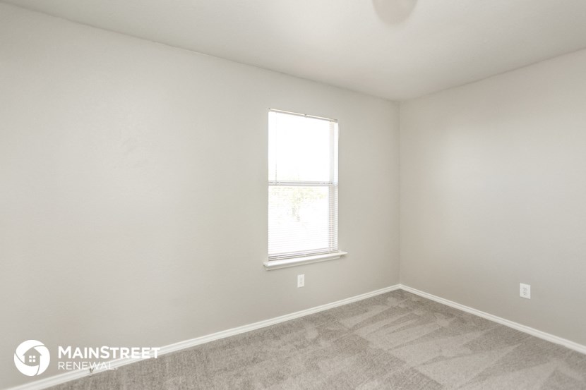 a bedroom with a window and a carpeted floor