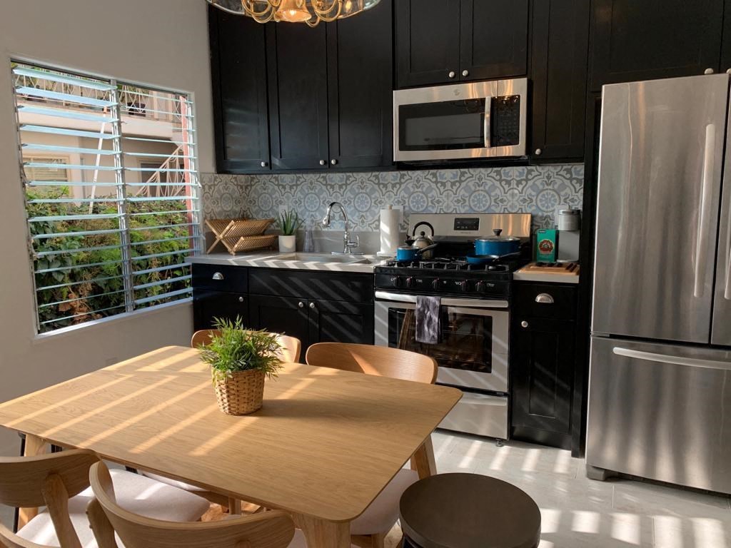 a kitchen with black cabinets and stainless steel appliances and a wooden table
