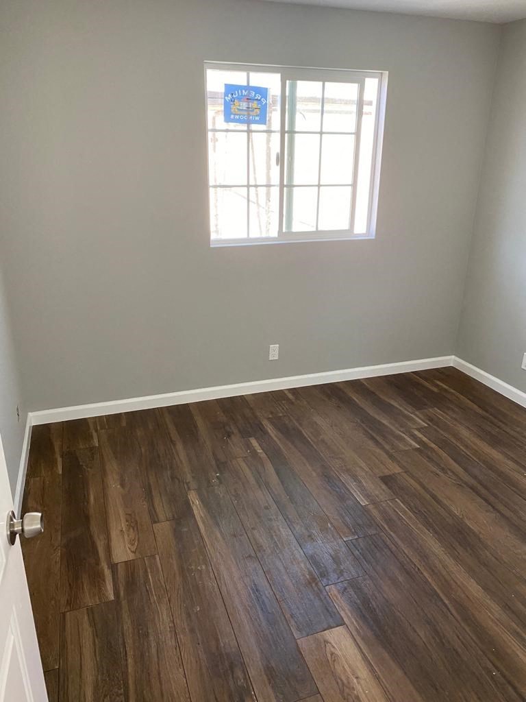 an empty room with wooden floors and a window