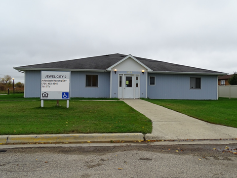 a blue building with a sidewalk and a sign in front of it