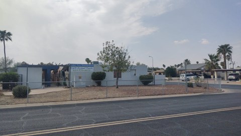A street view with a white building and a fence.