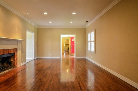 A spacious room with a fireplace and wooden floors.