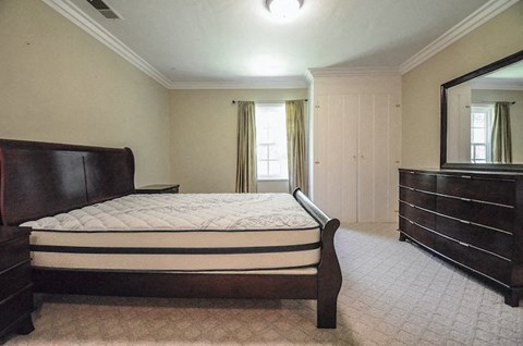 A bedroom with a large bed and a mirror on the wall.