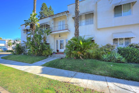 the front of a white house with a lawn and palm trees
