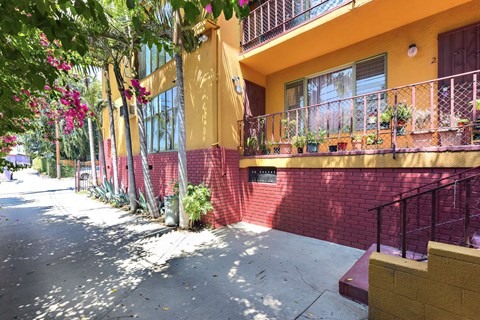 A yellow building with a red wall and a balcony.