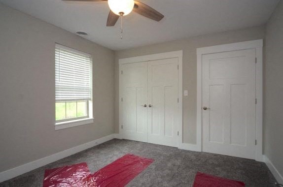 a empty bedroom with a ceiling fan and two doors