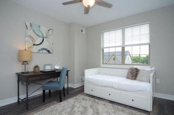 a bedroom with a bed and a desk and a ceiling fan