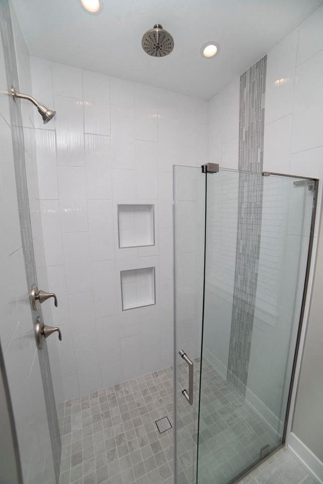 a large white tiled shower with a glass door