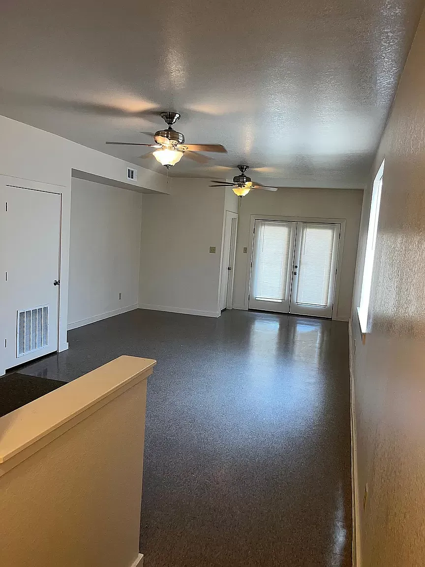 an empty living room with two ceiling fans