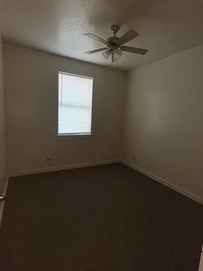 an empty room with a ceiling fan and a window