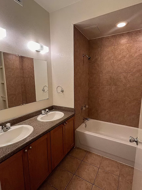 A bathroom with a brown tiled shower and a white bathtub.