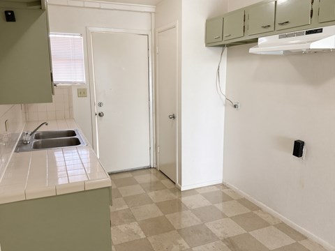 A kitchen with a sink and a checkered floor.