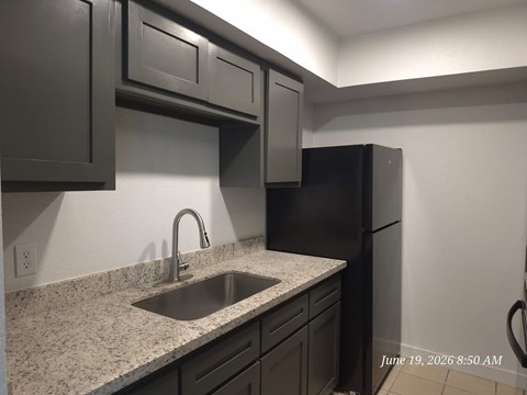 A kitchen with black cabinets and a granite countertop.