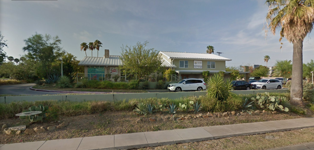 the front of a house with cars parked in a parking lot
