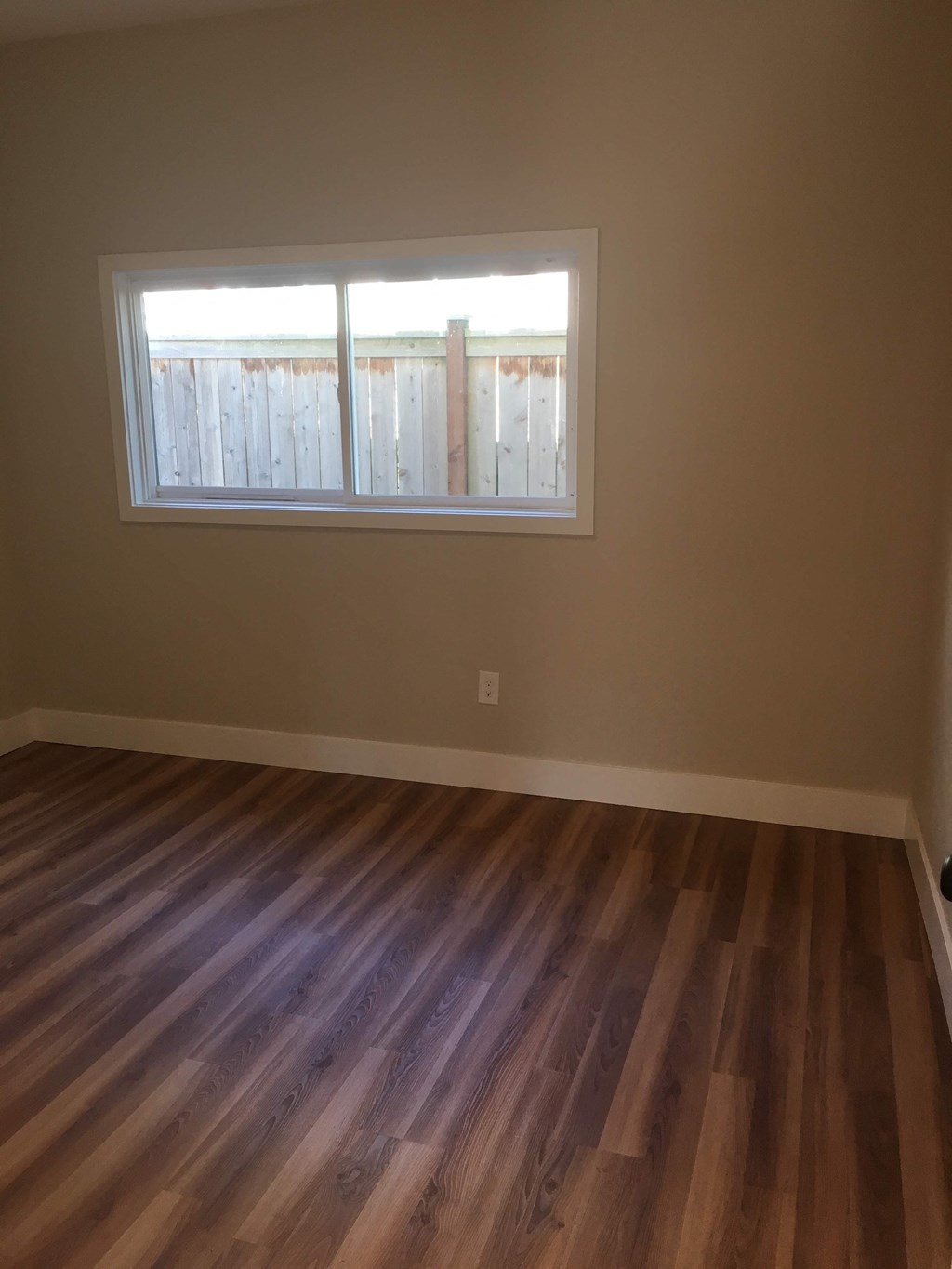 an empty room with wooden floors and a window
