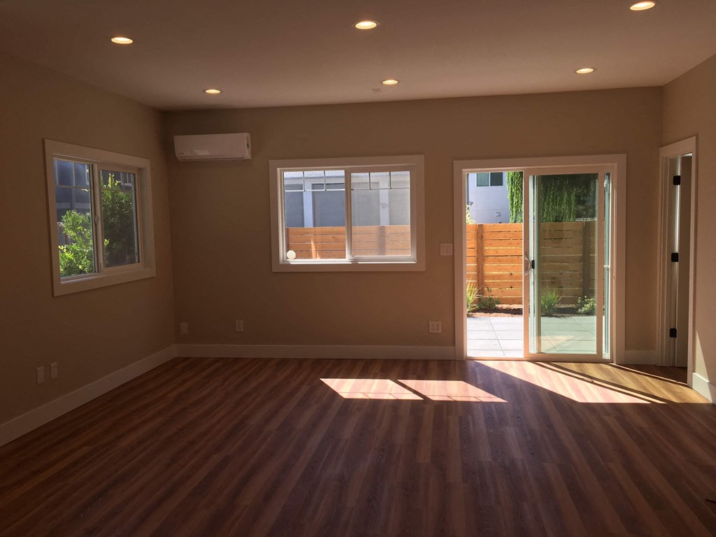 an empty living room with wooden floors and a glass door