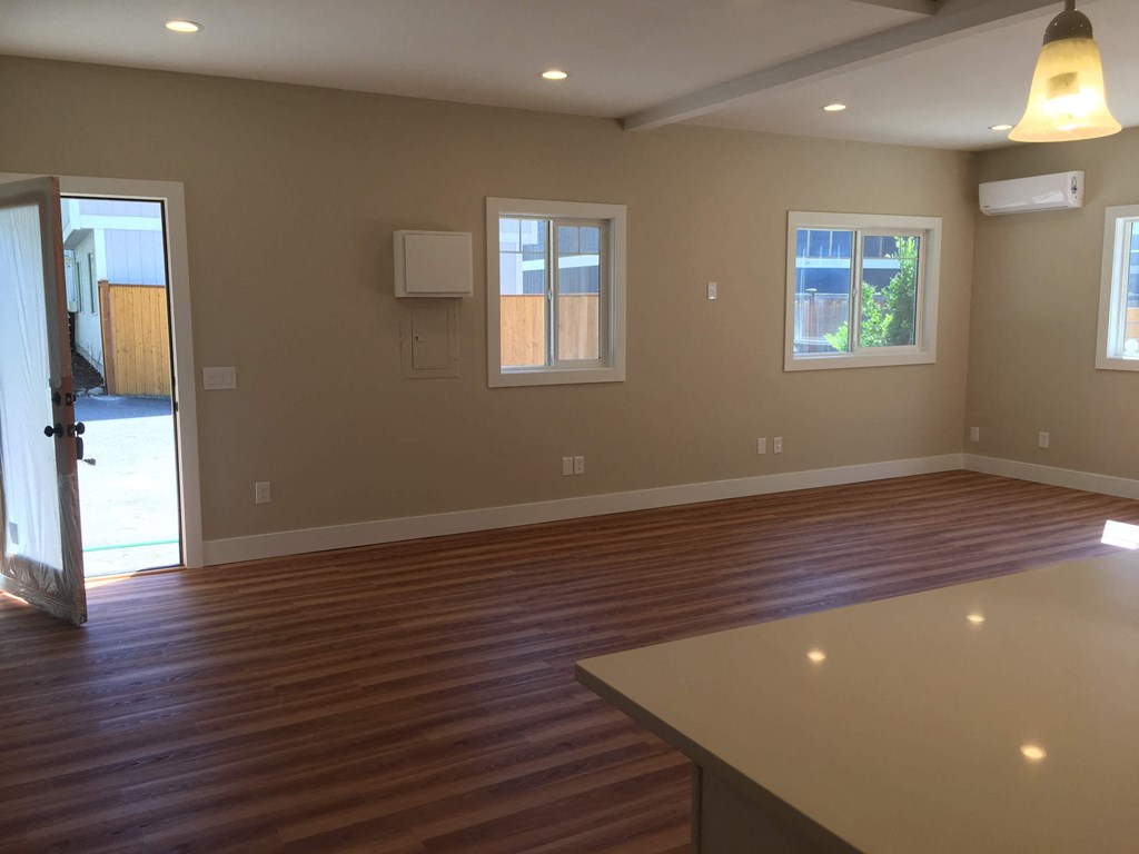 an empty living room with wooden floors and a window